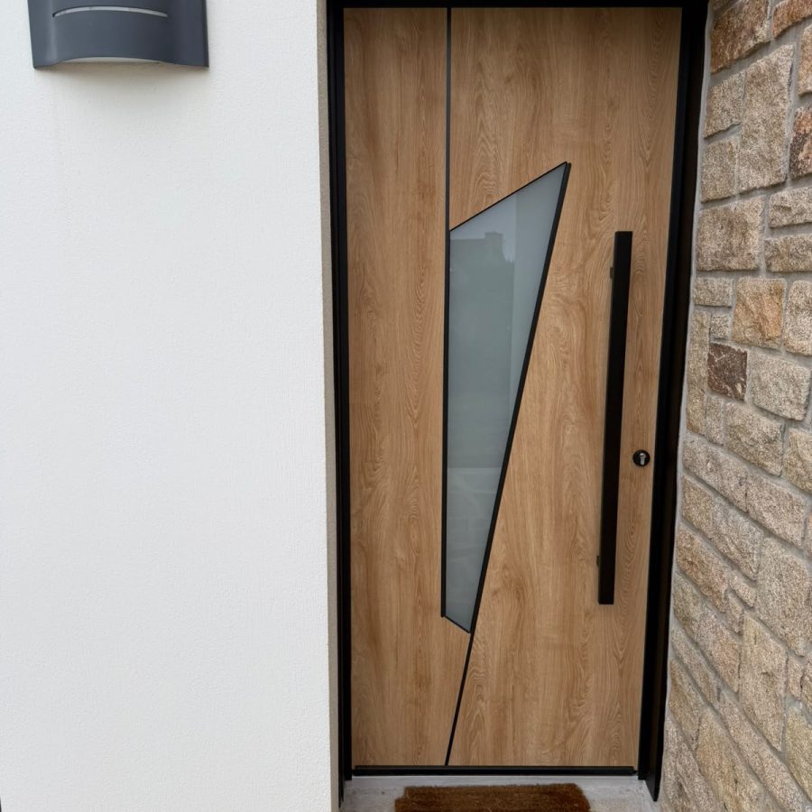 Porte d'entrée contemporaine aspect bois avec vitrage triangulaire et barre de tirage noire
