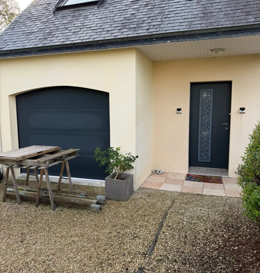 Porte de garage sectionnelle et porte d'entrée anthracite assorties sur une maison