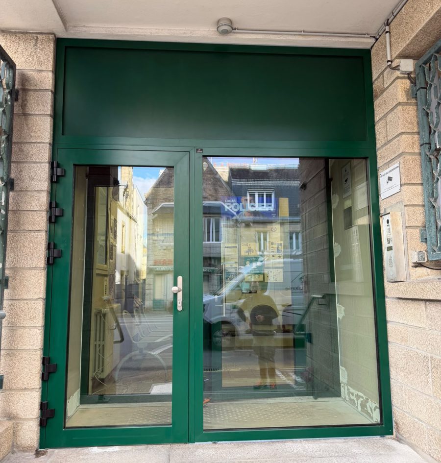 Porte vitrée à double vantail, teinte verte, à l'entrée d'un local professionnel