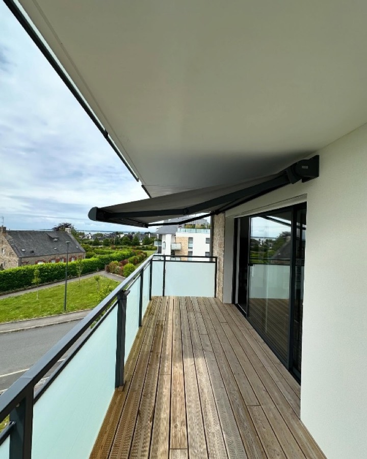 Store banne Franciaflex Félicia déployé au-dessus d'un balcon