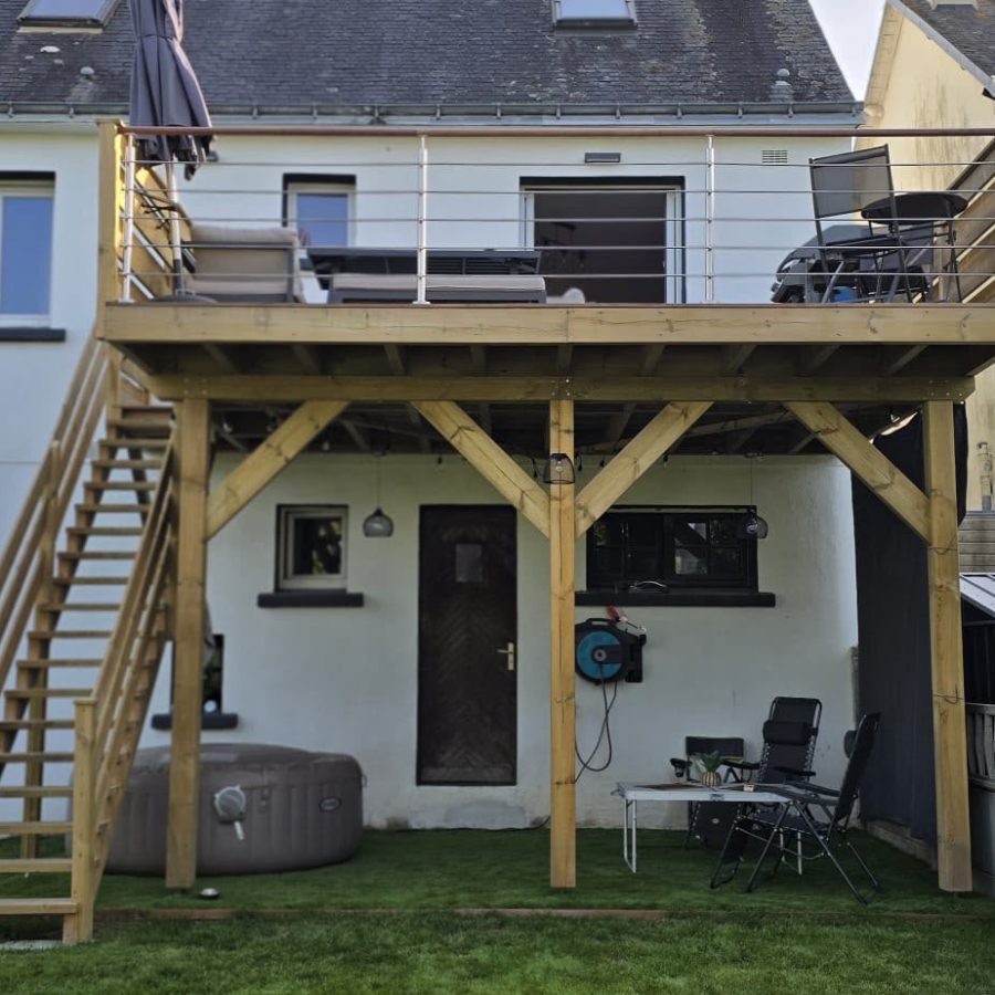 Terrasse surélevée en bois avec escalier et garde-corps à câbles, à l'arrière d'une maison